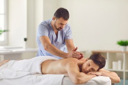Relieving back muscle tension. Professional masseur massaging young man's back using Tapotement or chopping, tapping or hacking technique during Swedish massage therapy in spa salon or wellness center