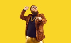 Happy funny plump young man singing songs and dancing gangnam style at a party. Funky redhead chubby guy having fun and doing rope dance move like cowboy with lasso isolated on amber color background