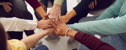People of different ages and nationalities fold their hands on each other, symbolizing their unity and support. Team of people who are set up for productive work and a positive result. Close up.