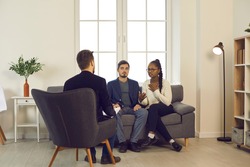 Couple experiencing relationship problem having therapy session at marriage and family therapist's office. Young multiracial people trying to resolve conflict with help of professional psychologist