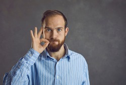 Headshot of confident handsome young caucasian guy showing secret silent gesture asking stop talking keep silence asking be quiet. People emotion and expression face portrait and confidentiality