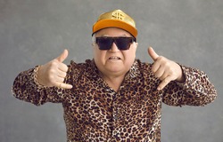Cool retired gangsta granddad flexing to rap music. Portrait of funny weird active rich senior man in baseball cap, trendy eyeglasses and leopard patterned party shirt posing and having fun in studio