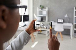 Black designer taking office interior photos, making presentation or video calling client using smart phone app. Rental agent or realtor shows work space while giving tour around display apartment