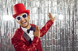 Happy young black man in red disco jacket dance on glitter background. Smiling African American entertainer or showman have fun on party or celebration in nightclub. Entertainment concept.