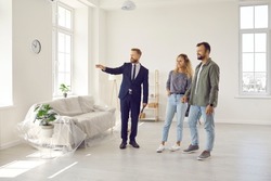 Real estate agent giving potential buyers or future tenants tour about big new house. Boyfriend and girlfriend or husband and wife who plan property investment looking at lovely modern spacious home