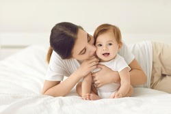Loving young mother kiss little newborn baby enjoy maternity leave at home. Caring mom cuddle hug small infant child or kid. Mothers day celebration. Happy motherhood or parenthood. Childcare.