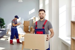 Smiling young male deliveryman or mover hold cardboard box pack belongings in client office or home. Happy man worker from removal or deliver company unload packages. Moving and relocation.