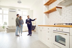 Male relator or broker show home to couple buyers or renters buying fist dwelling together. Man real estate agent demonstrate apartment to tenants. Homeowner, bank loan or mortgage, rent.