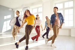 Group of happy beautiful young people enjoying a contemporary dancing class. Team of cheerful smiling dancers in casual wear practising a new choreo and having a good time together in a modern studio