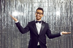 Portrait of smiling African American male entertainer amuse on disco glitter background in club. Happy black man mc or magician do tricks entertain audience in nightclub. Entertainment concept.