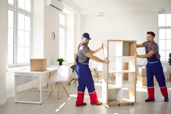 Smiling carriers help customer with furniture during relocation and moving day. Deliverymen or movers in uniform carry shelves work for client at office or new home settle. Transportation concept.