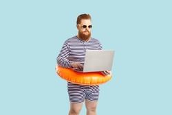 Funny man finds time for business during summer holiday at seaside. Serious chubby entrepreneur working on computer while on vacation. Busy plus size guy in striped swimsuit using his laptop at beach