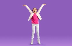 Overjoyed teen girl child isolated on violet studio background have fun jumping and laughing. Smiling teenage kid in casual wear show height excited about being tall. Childhood growing up.