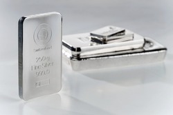 Minted silver bar against a background of a stack of various silver ingots. Selective focus.