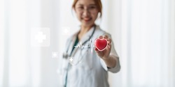 Cardiologist holding red heart in private clinic. Medical technology diagnostics of heart concept.