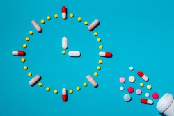 Clock made from colorful pills as a concept of taking medicine in time, by prescription. Addiction from drugs, painkiller capsules.