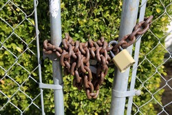 Lock and Chain. A rusty steel chain with a padlock securing a fence closed. Locks and Chains have been used for years to keep people in or out of various places. 