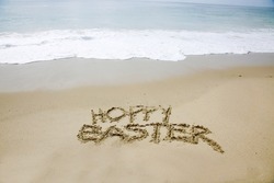 Hoppy Easter. The words HOPPY EASTER written in the sand by the ocean. Easter Sunday is a day to celebrate at the beach or anywhere you like. Hoppy Easter to all. 