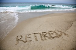 RETIRED Word written in the sand. Laguna Beach, California with the word RETIRED. Pacific Ocean with the word Retired hand written in the wet sand of Laguna Beach, California. Relax your Retired. 