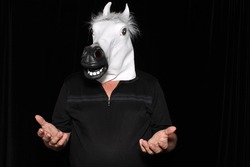 An unidentifiable man wears a White Rubber Horse Head Mask while in a Photo Booth.
