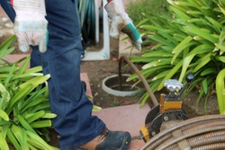 Sewer cleaning. A plumber uses a sewer snake to clean blockage in a sewer line. 