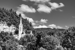 St. Martin Parish Church in Bled, Slovenia. Church of St Martin, a small white neo-gothic church surrounded by green trees on top of a rock hill
