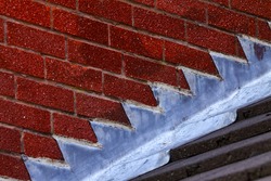 Stepped lead flashing roof gulley creating a water tight seal between roof tiles and brick wall on a domestic house