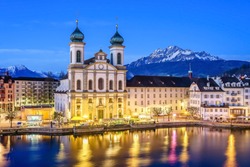 The lights of the Jesuit Church (Jesuitenkirche in German) reflecting in the Reuss river at night in Lucerne, Switzerland