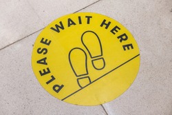 footprint sign for stand in shopping mall, supermarket. Social distancing with COVID-19 coronavirus crisis. yellow footprint sign with text caution social distance