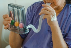 Asian woman patient using incentive spirometer inhalation exercise pulmonary alveoli restore breath training lung capacity physical therapy covid19