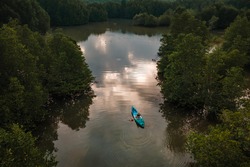 Young woman tourist paddling the kayak at Salak Khok mangrove forest with aerial drone shot, Koh Chang, Thailand