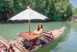 Young woman tourist sitting the boat at Salak Khok mangrove forest with aerial drone shot, Koh Chang, Thailand