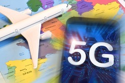 Model airplane on geographic map and smartphone with 5G text on screen. Conceptual image for concerns about possible transmission interference to aircraft.