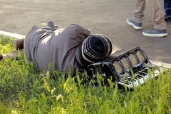 A Homeless man and his accordion sleeping in the park 