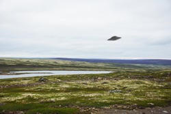 Flying saucer UFO over tundra in the Kola Peninsula in Russia. UFO floating above tundra landscape near Teriberka village