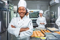 Smiling african  female bakers looking at camera..Chefs  baker in a chef dress and hat, cooking together in kitchen.Team of professional cooks in uniform preparing meals for a restaurant in   kitchen.