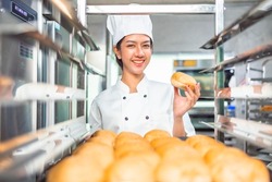 Smiling  asian  female bakers looking at camera.Chefs  baker in a chef dress and hat, cooking together in kitchen.Team of professional cooks in uniform preparing meals for a restaurant in   kitchen.