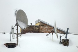 Snowstorm. A lot of snow on the roof and the satellite dish in the winter. Chimney covered with snow