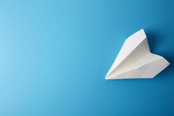 Flat lay of white paper plane and blank paper on pastel blue color background.Horizontal