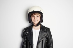 Portrait of Young happy beautiful teen kid in black leather jacket and white moto helmet smiling on white background
