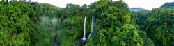 Panormaic of two large waterfalls surrounded by dense rainforest
