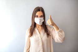 Young woman wearing medical face mask, studio portrait. Woman Wearing Protective Mask and Showing OK sign. Woman wearing surgical mask for corona virus. 