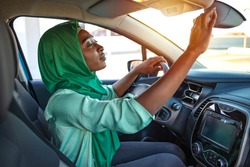 Muslim women are adjusting the rearview mirror of the car. Safety driving woman adjust the car rearview mirror in interior before start travel trip every time. Muslim woman driving a car