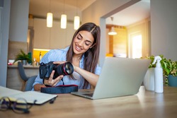 Woman working on laptop in home. Freelance photographer edit photos on computer. Professional photography business. Girl workspace with computer and photo camera. Creative artist lifestyle