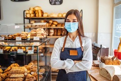 Woman working at a bakery wearing a facemask to avoid the coronavirus. COVID-19 lifestyle concepts. Day in the life of owners of bakery shop with the protocol against the Covid-19 in place. 