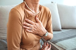 Woman having a pain in the heart area. Heart Attack. Painful Chest. Health Care, Medical Concept. High Resolution. Woman having heart attack at home. 