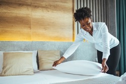Maid working making the bed at a hotel. Housekeeper making the bed at a hotel. Female Hand set up white bed sheet in bedroom. Chambermaid Making Bed