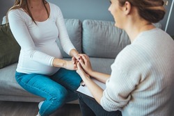 Pregnant woman on home counselling meeting. You're not in this alone. Depressed pregnant woman consultation with psychologist. Psychiatrist holding hands patient,such as making a fresh start