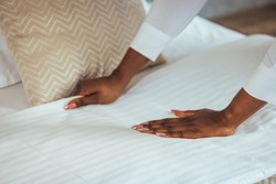 African maid making bed in hotel room. Staff Maid Making Bed. African housekeeper making bed. Maid working at a hotel making the bed. Housekeeper cleaning a hotel room