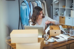 A business woman packs a shipping package. The online business owner prepares the order and sends the delivery box to the customer. Work from home. Home office.